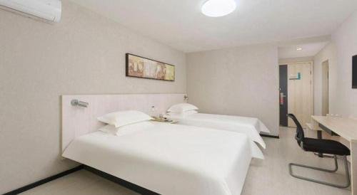 a hotel room with two beds and a sink at Jinjiang Inn Dalian Development Zone Jinma Road Light Railway Station in Jinzhou