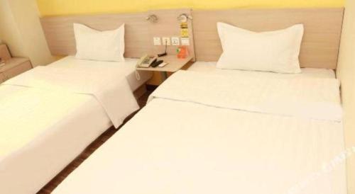 two white beds in a room with a telephone at 7 Days Inn Tianjin Binhai New District Yujiabao Metro Station in Binhai