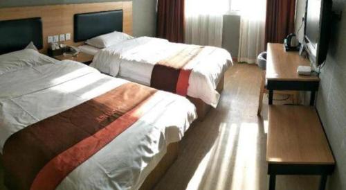 a hotel room with two beds and a television at Jun Hotel Jiangsu Nanjing Gulou District Gupinggang in Nanjing