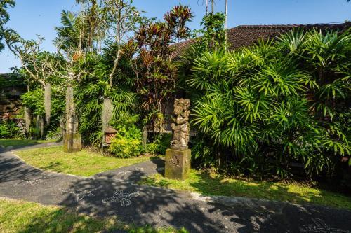 a stone pillar in front of a house with trees at Mumbul Ubud in Ubud