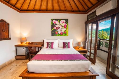 a bedroom with a bed and a desk and a window at Mumbul Ubud in Ubud
