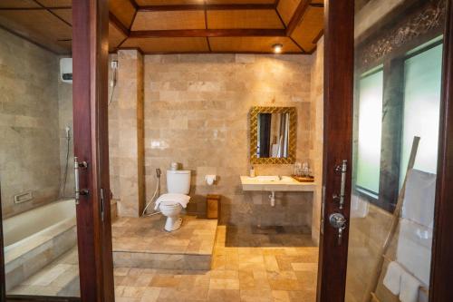 a bathroom with a toilet and a tub and a sink at Mumbul Ubud in Ubud