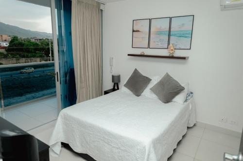 a bedroom with a white bed and a balcony at Hermoso apartamento. Cerca del mar. in Santa Marta