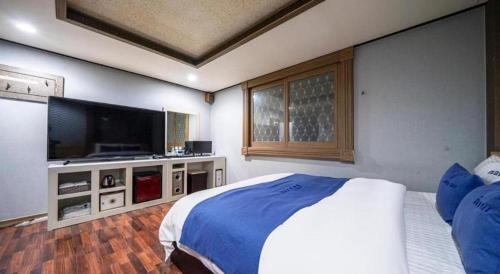 a bedroom with a large bed and a flat screen tv at SKY Hotel in Changwon