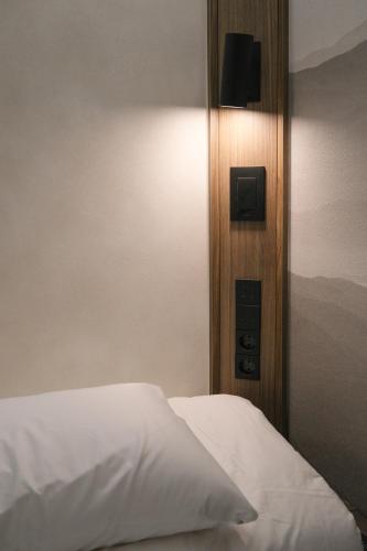a bedroom with a white bed with a light on the wall at GOYOO INN & cabins in Seoul