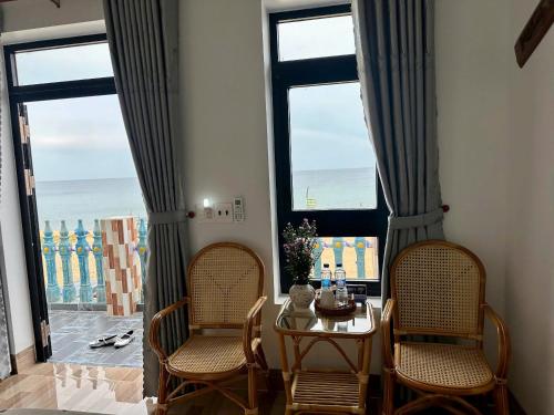 Phú HiệpにあるBien Xanh Homestayのダイニングルーム(椅子2脚、テーブル1台、窓2つ付)