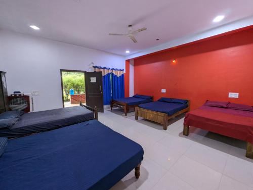 a bedroom with three beds and a red wall at Rasta Homestay Sakleshpur in Sakleshpur
