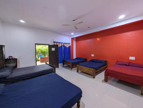 a bedroom with three beds and a red wall at Rasta Homestay Sakleshpur in Sakleshpur