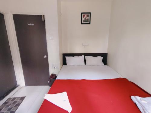 a red and white bed in a small room at Hotel Harmony heights in Pune
