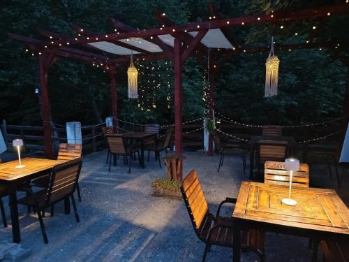a patio with wooden tables and chairs and lights at Complex Adela Transfăgărășan in Cîrţişoara