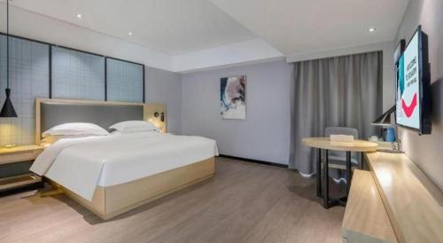 a bedroom with a large bed and a table at Echarm Hotel Beihai Railway Station in Beihai