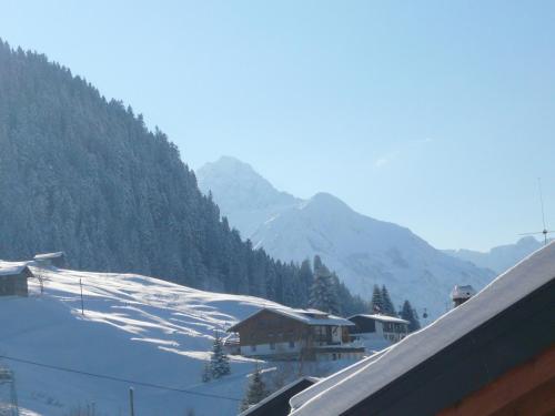 a snow covered mountain with a house in the foreground at Denninger's Ferienhäusle in Riezlern