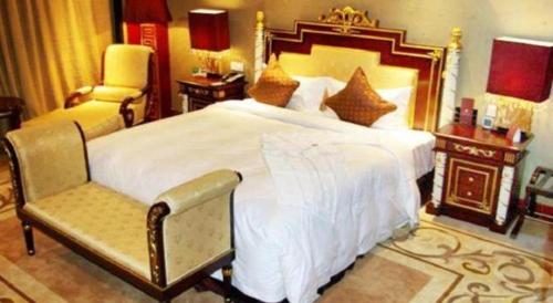 a bedroom with a large white bed and a chair at Dunhuang Grand Soluxe Hotel in Dunhuang