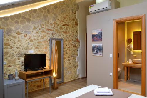 a bedroom with a tv and a stone wall at Elia Kentron in Chania Town