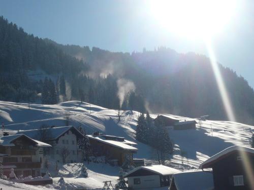 a snow covered village with the sun shining on a mountain at Denninger's Ferienhäusle in Riezlern