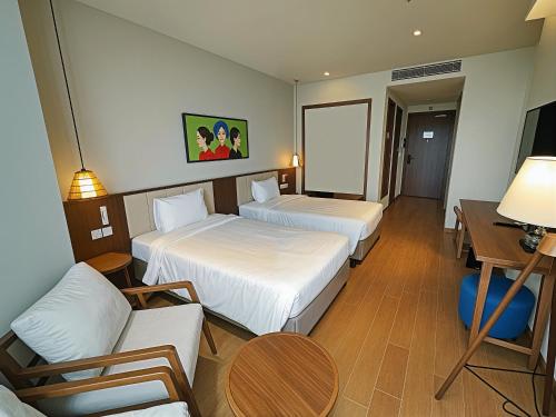 a hotel room with two beds and a couch at Mandala Oceanfront Driftwood Resort in Phan Thiet