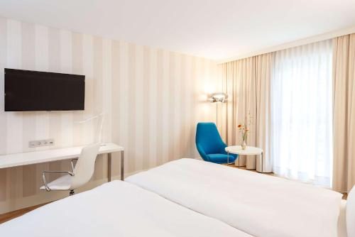 a hotel room with a bed and a tv and a chair at NH Essen in Essen