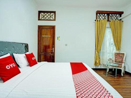 a bedroom with a large bed with red and white at OYO 92990 Nena Kostel Syariah in Padang