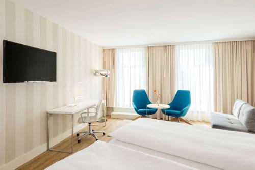 a hotel room with a desk and blue chairs at NH Essen in Essen