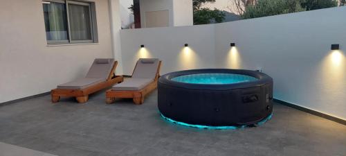 a patio with a hot tub and two chairs at Castalia Naiades Suites in Ialysos