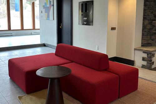 a red couch in a living room with a stool at Park Inn by Radisson, Sydney in Sydney