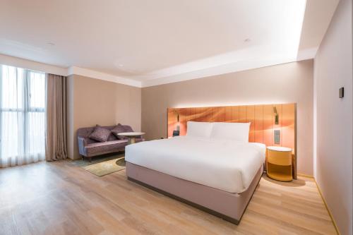 a hotel room with a bed and a chair at Manxin Hotel Guangzhou Baiyun Airport Branch in Guangzhou