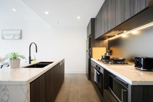 a kitchen with a sink and a counter top at Olympic Park 1Br modern apt near train shops with pool in Sydney