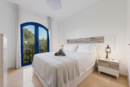 a white bedroom with a bed and a window at Brisa del Puerto de la Duquesa in Manilva