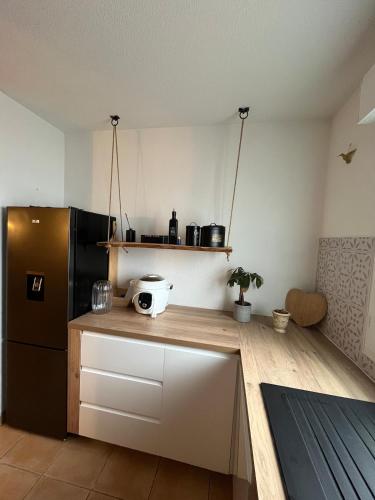Il comprend une cuisine équipée d'un réfrigérateur noir et d'un comptoir en bois. dans l'établissement Terrasse avec parking, à Uzès