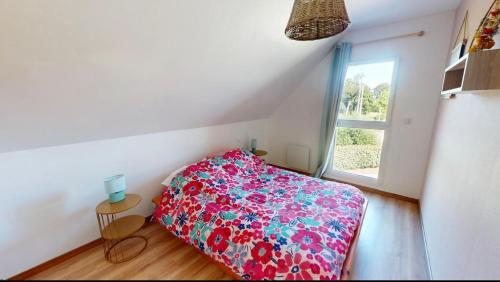 - une chambre avec un lit doté d'un couvre-lit floral et d'une fenêtre dans l'établissement Gîte de La Durantais, à Epiniac