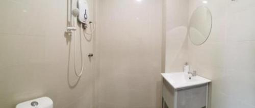 a white bathroom with a shower and a sink at Rock & Roll Hotel Klang in Klang
