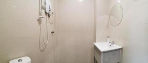 a white bathroom with a shower and a sink at Rock & Roll Hotel Klang in Klang