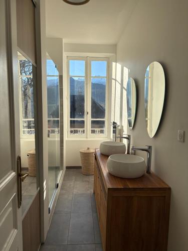 une salle de bain avec deux lavabos et deux miroirs dans l'établissement Superbe maison de vacances au centre d’embrun, à Embrun