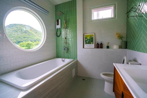 a bathroom with a tub and a window and a sink at Queenstown Khaoyai in Pak Chong