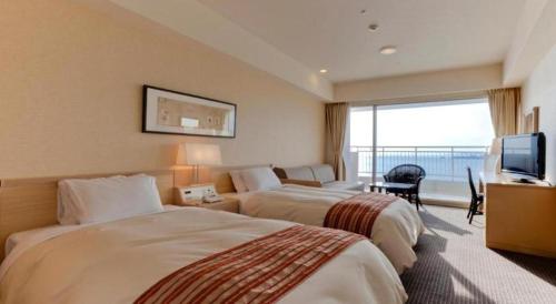 a hotel room with two beds and a television at Hotel Harvest Nankitanabe in Tanabe