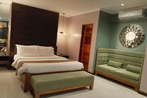 a bedroom with a bed and a chair and a mirror at Hotel Lapira Vigan in Vigan