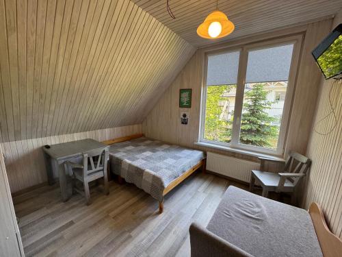 a room with a bed and a table and a window at Gintaro Vila in Kunigiškiai