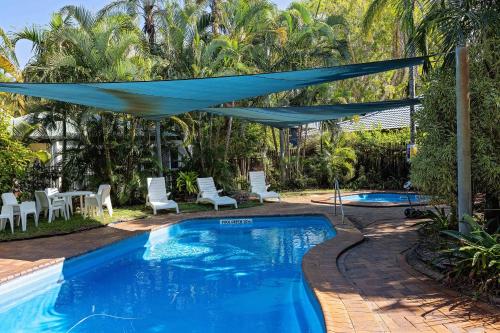a swimming pool with a blue canopy over it at The Shores Holiday Apartments in Mackay