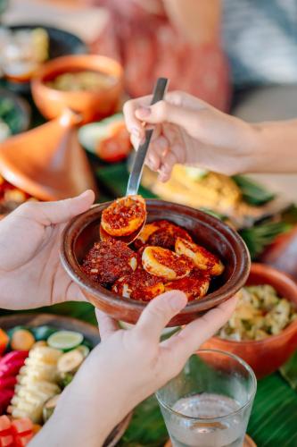 a group of people holding up a bowl of food at Qunci Villas Resort in Senggigi 