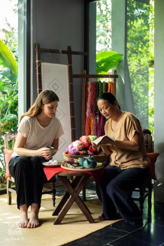 two women sitting next to a table with a cake at Le Clos Du Fil in Ninh Binh