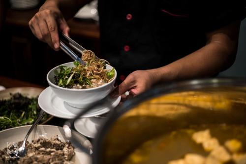 a person is eating a bowl of food with tongs at Le Clos Du Fil in Ninh Binh