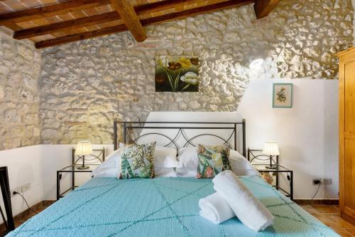 a bedroom with a blue bed in a stone wall at Casa Vacanze Etrusco in San Gimignano
