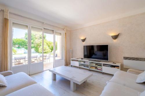 un salon blanc avec une télévision et une table dans l'établissement Villa La Perle l Pool & Terrace l Shellter Rentals, à Saint-Tropez