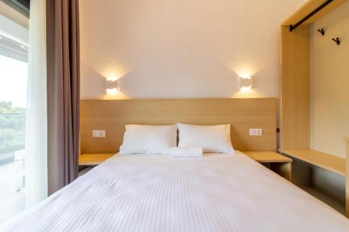 a bedroom with a white bed with two pillows at SithoniaRS White Sand Luxury Maisonette in Neos Marmaras