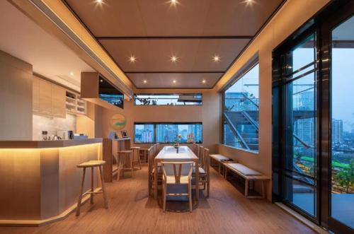 a restaurant with a table and chairs and large windows at 隐栖堂酒店 成都太古里合江亭店 in Chengdu