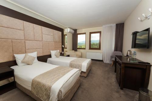 a hotel room with two beds and a television at Family Hotel The View & SPA in Tsigov Chark