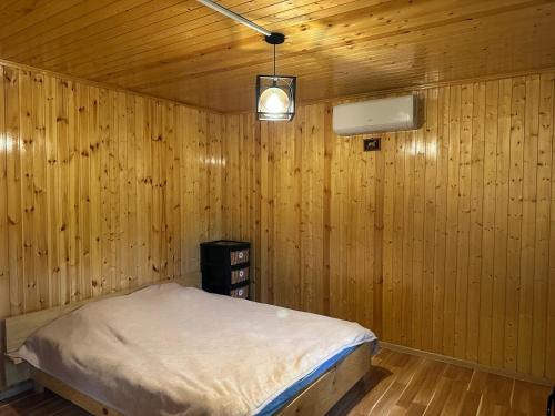 a bedroom with a bed in a wooden wall at Sunset Krikhi in Ambrolauri