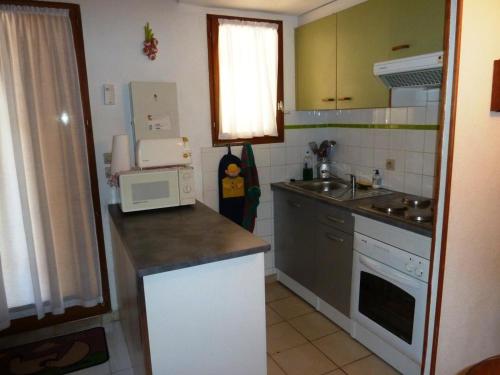 une petite cuisine avec un évier et un micro-ondes dans l'établissement Villa calme climatisée idéalement située Mer Port Centre, à Saint Cyprien Plage