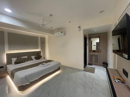アーメダバードにあるHotel The Indra Palaceのベッドと薄型テレビのある寝室