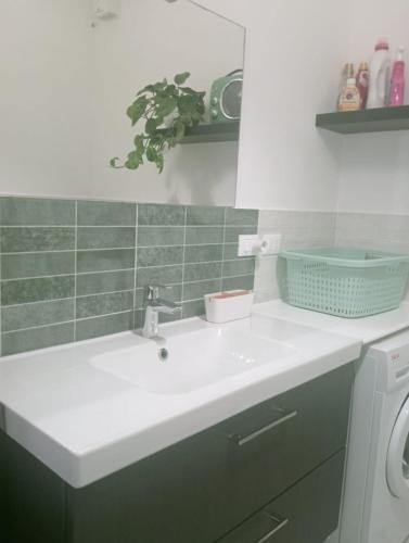 a bathroom with a white sink and a green tile wall at CASA L'UNICORNO con giardino privato in Levanto
